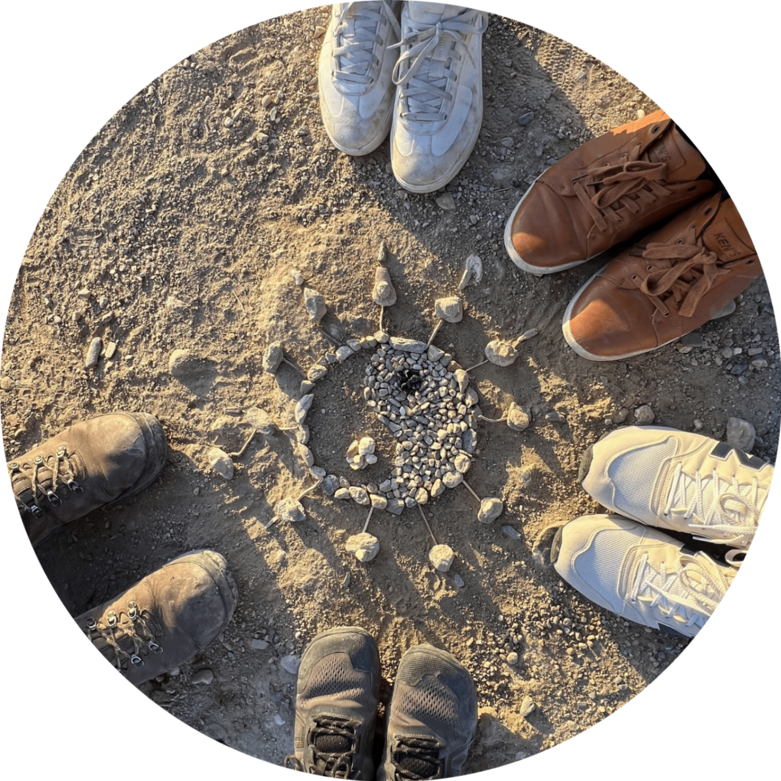 A circle of feet around a stone mandala on the earth