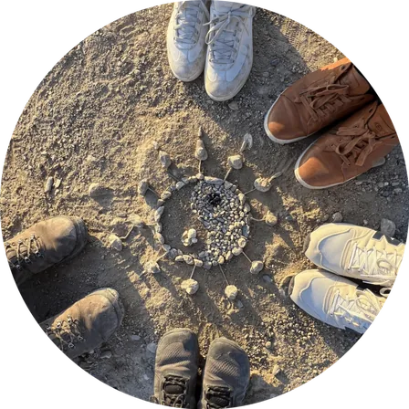 A circle of feet around a stone mandala on the earth